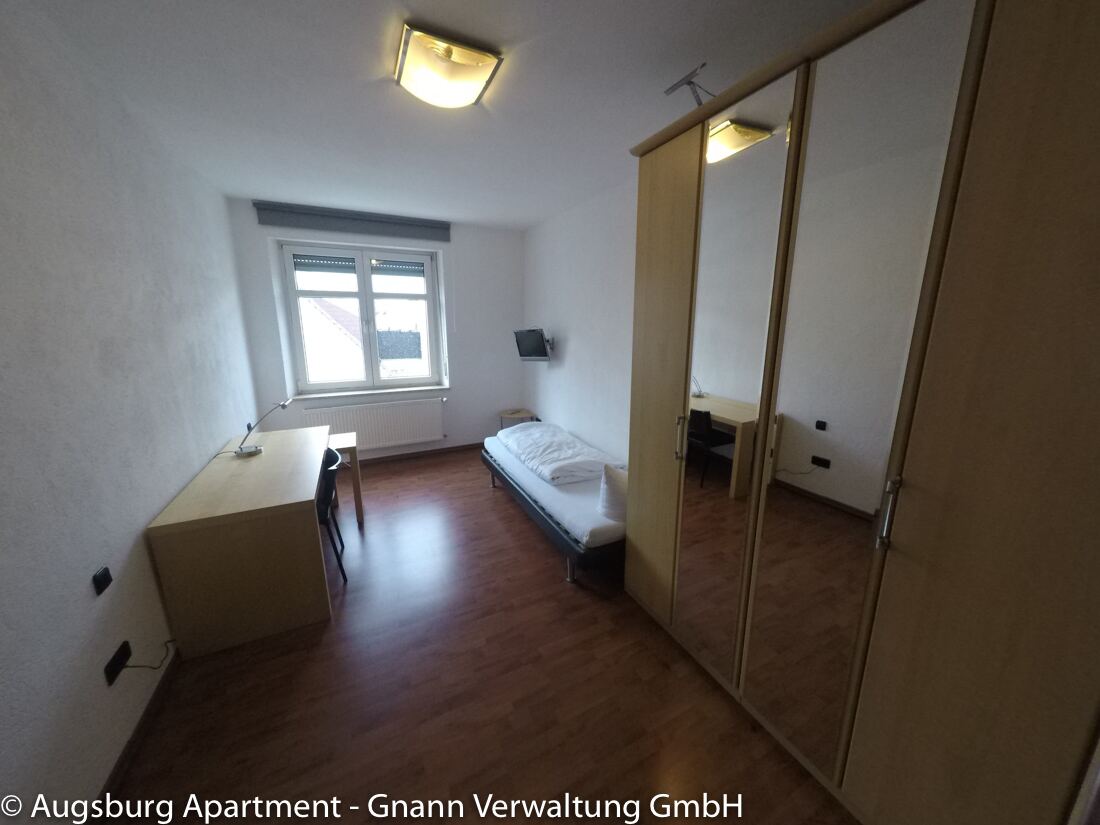 Zimmer mit Schreibtisch als Arbeitsplatz, Bett und Kleiderschrank in einer möblierten Wohnung in Augsburg