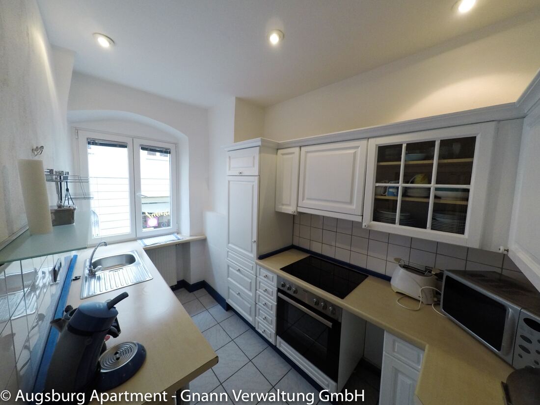 Voll ausgestattete Küche mit Herd, Backofen und Mikrowelle in einem Apartment in Augsburg