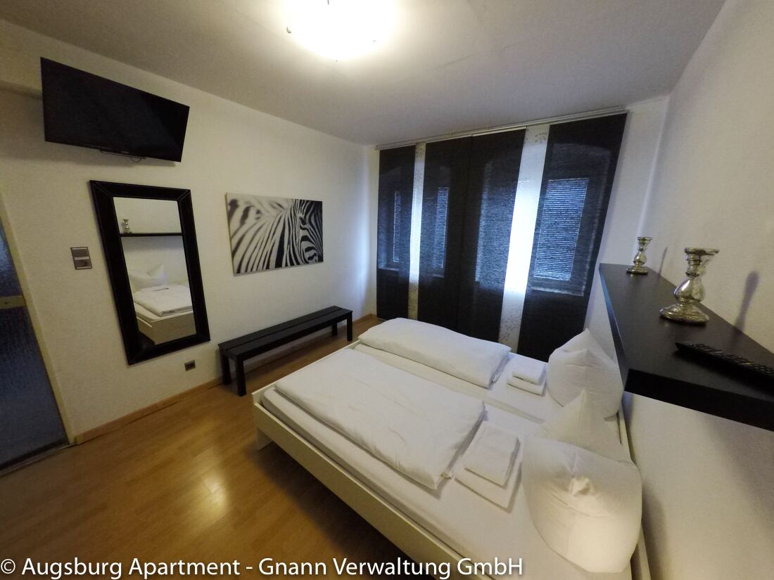 Schlafzimmer mit bezogenem Doppelbett in einer möblierten Wohnung auf Zeit in Augsburg