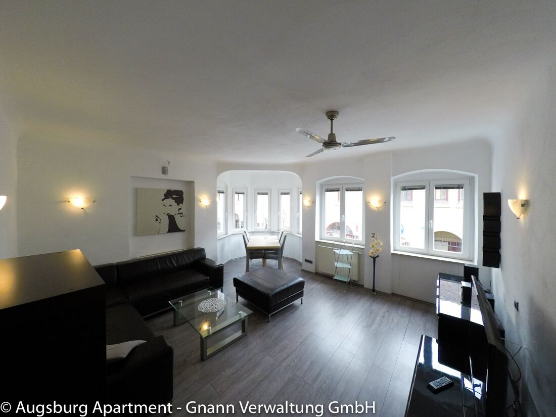Helles Wohnzimmer mit Ledersofa und Essplatz in einem möblierten Apartment in Augsburg